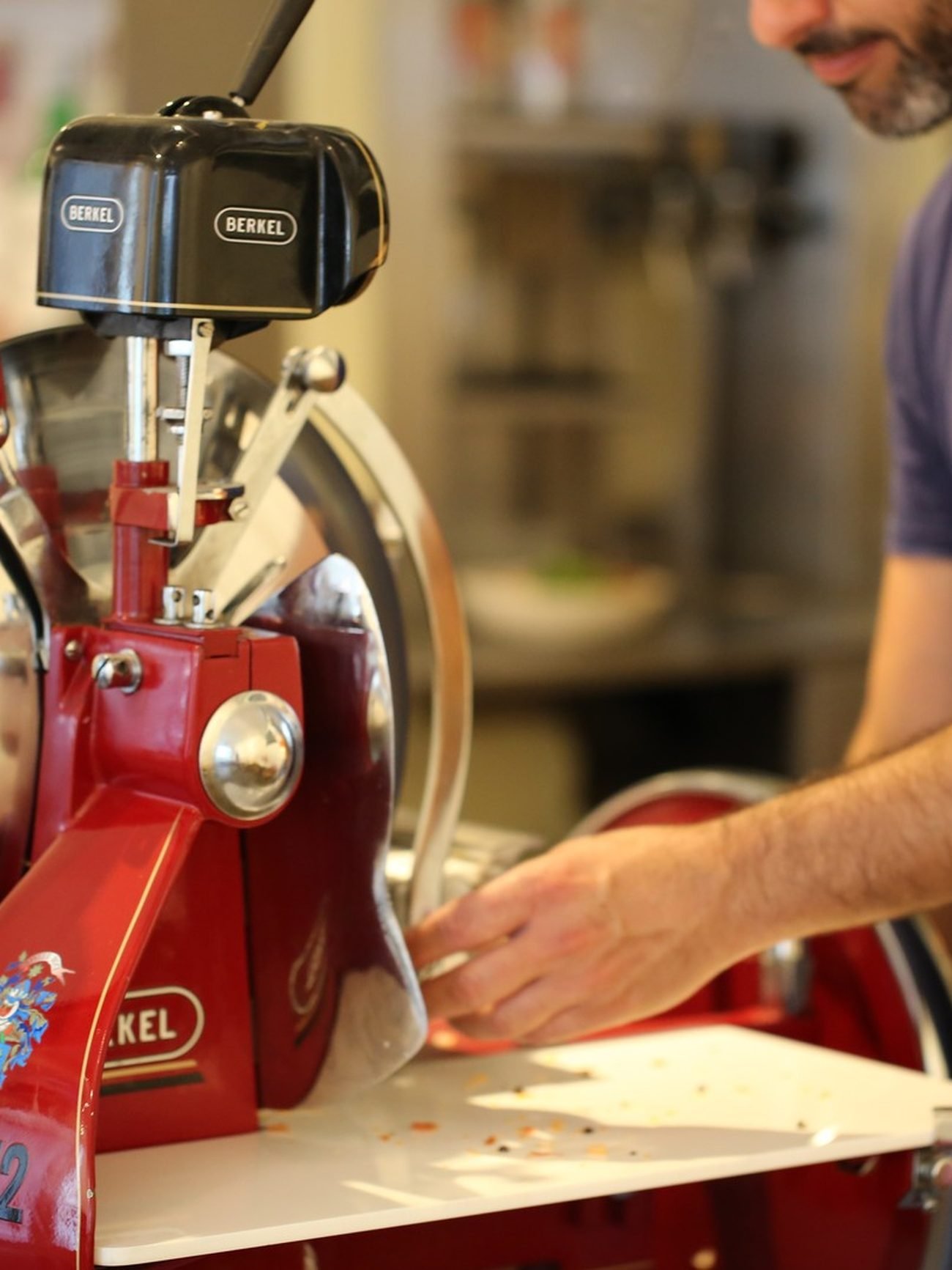 Cured meat being sliced on a red Berkel slicer